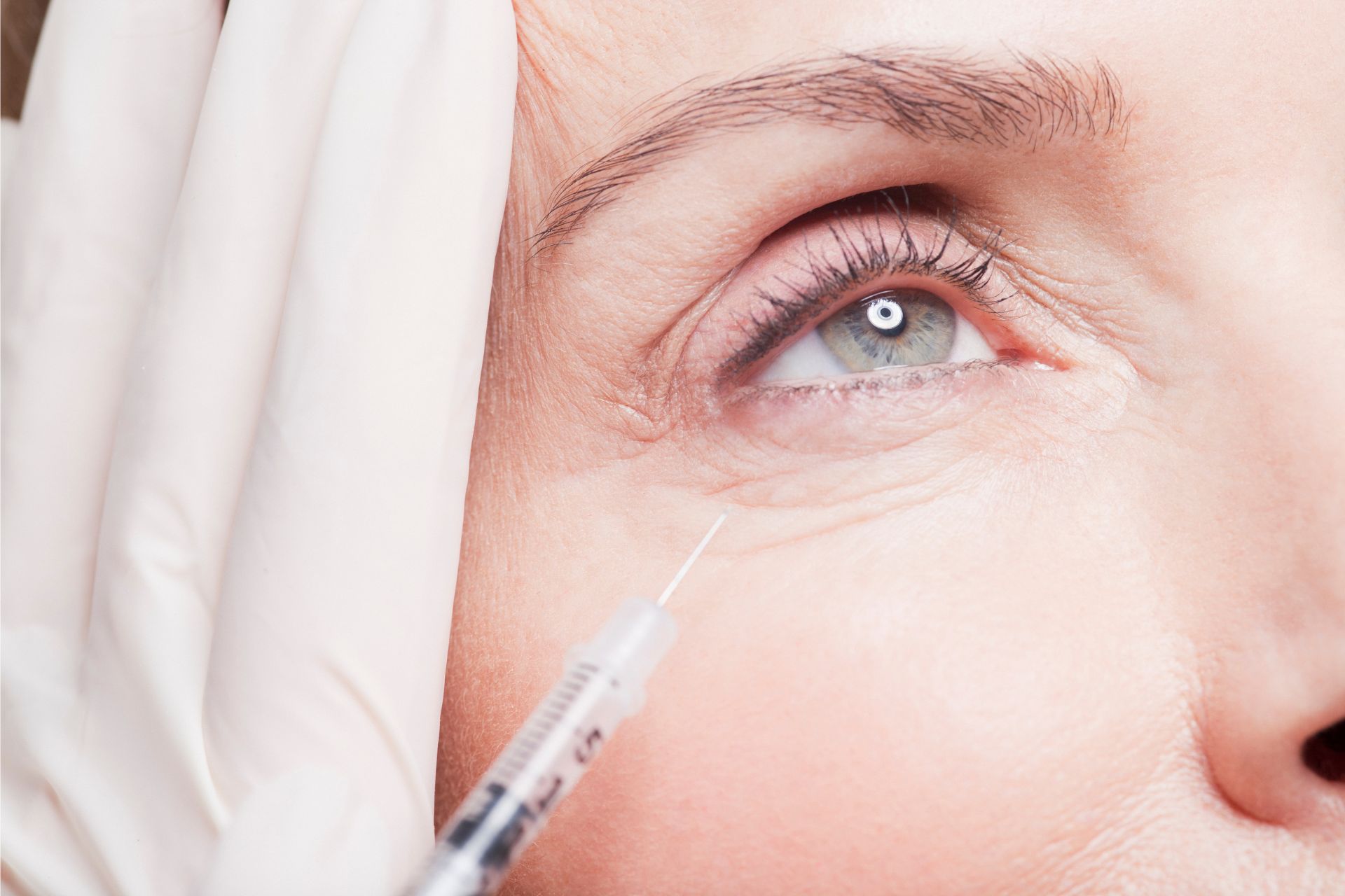 An older person getting filler injection in between her upper cheeks and lower eyelid