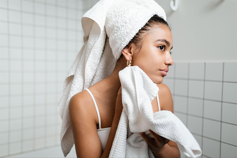 Woman fresh from the shower, drying her face with a towel 