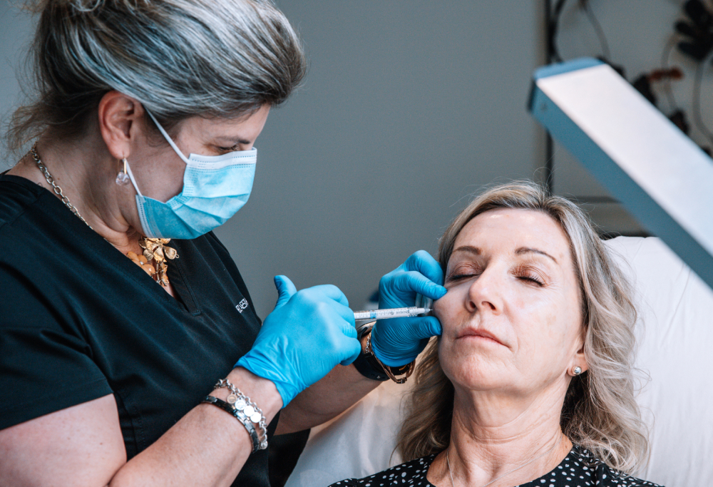 A medical aesthetician performing dermal filler injections on a female patient
