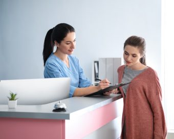 a receptionist at a medspa speaks with a patient about her intake forms
