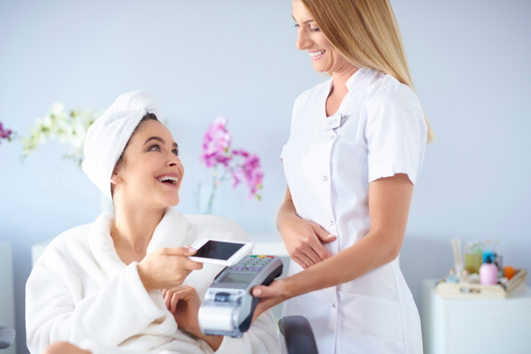  A spa customer tapping their phone on a POS system to pay for their treatment 